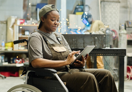 A woman in a wheelchair uses a tablet to access a disability cover payout paid into her bank account.